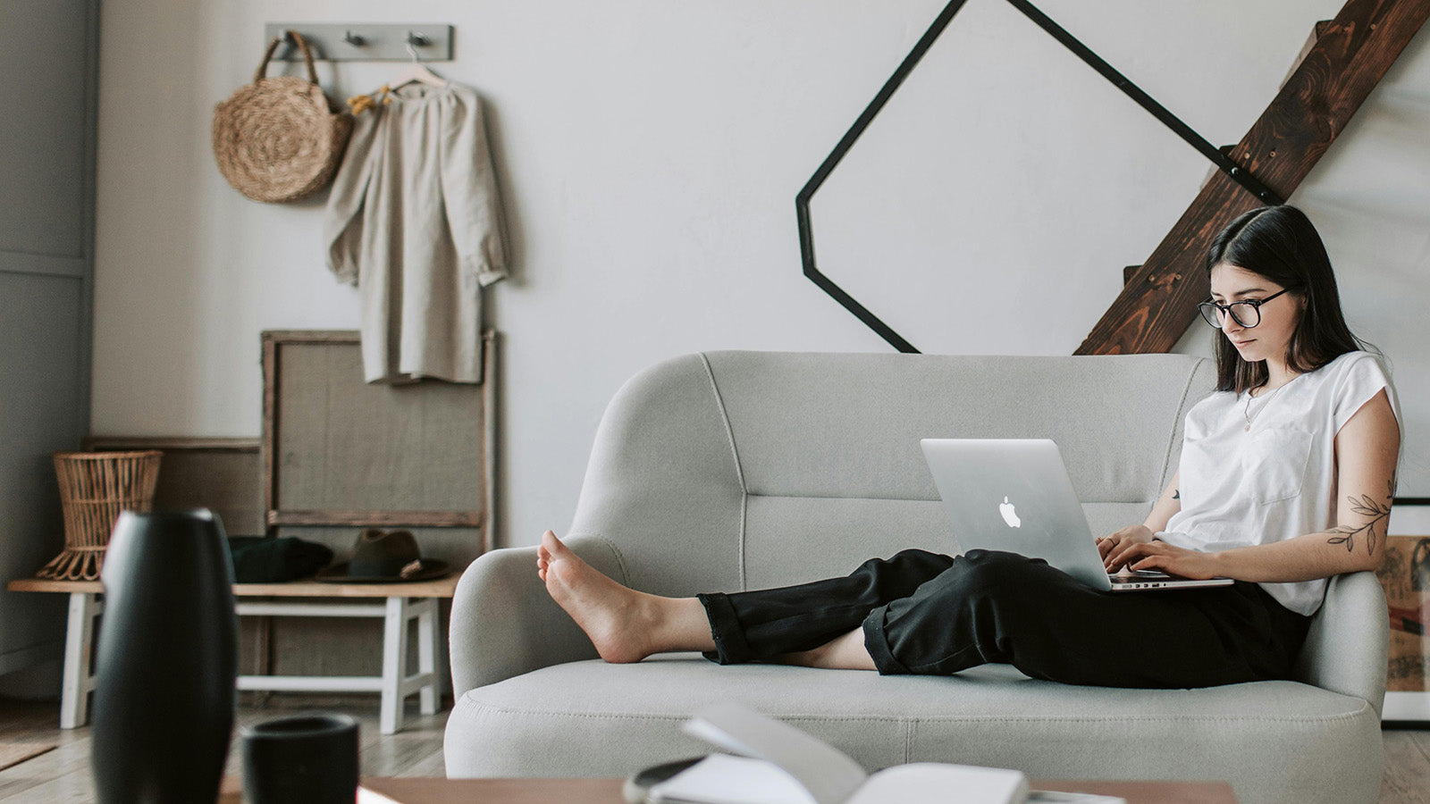Woman using a laptop on a gray sofa in a modern living room.